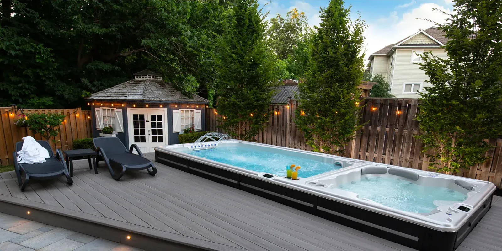 Hydropool swimspa med dubbelzon, simzon och spabad, på ett trädäck med solstolar och ett lusthus i trädgården